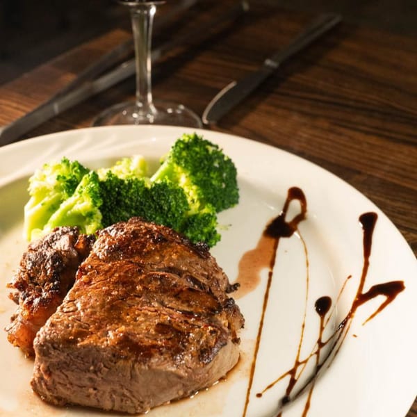 Birkin's Steakhouse and Sushi Bar's steak with broccoli and balsamic glaze on a white plate.