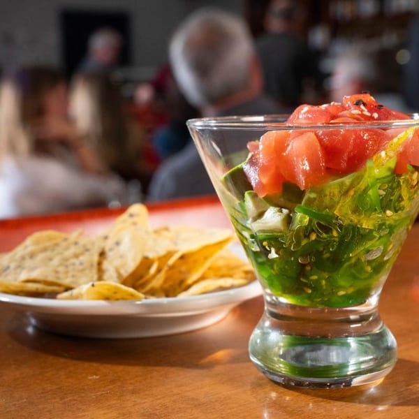 A martini glass of tuna poke with seaweed and avocado, next to tortilla chips at Birkin's Steakhouse.