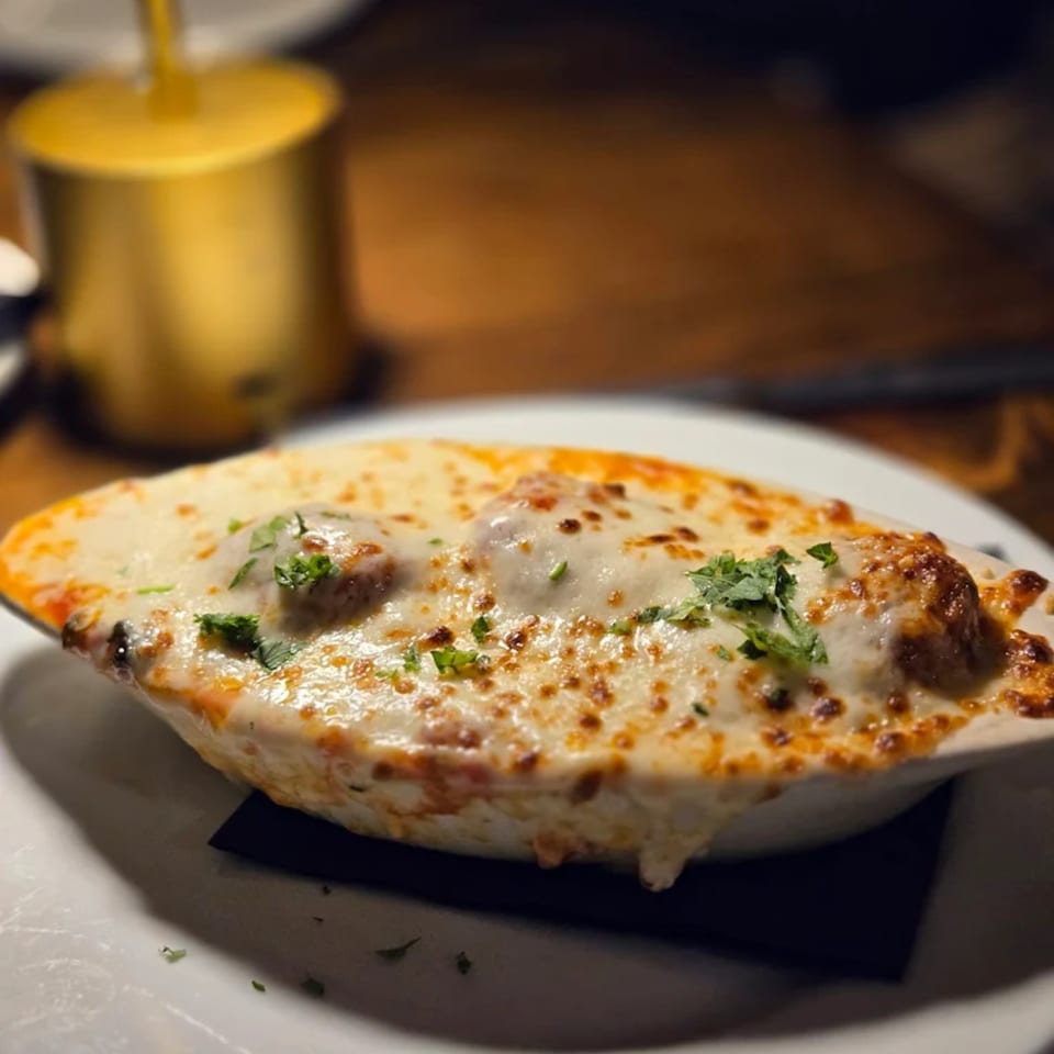 Birkin's Steakhouse and Sushi Bar's baked meatballs with melted cheese and herbs in a white dish.